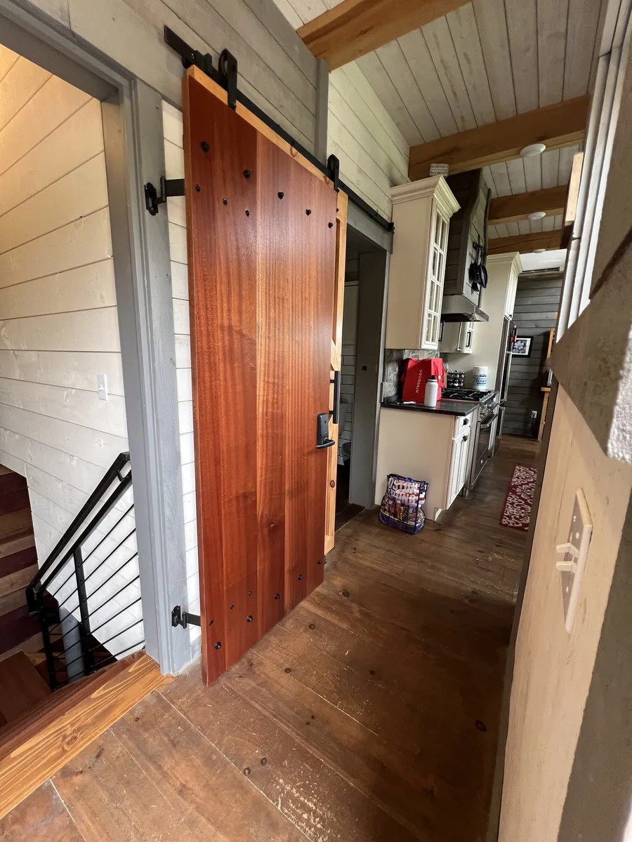 Custom sliding barn door in a shiplap hallway by DeFaria Construction