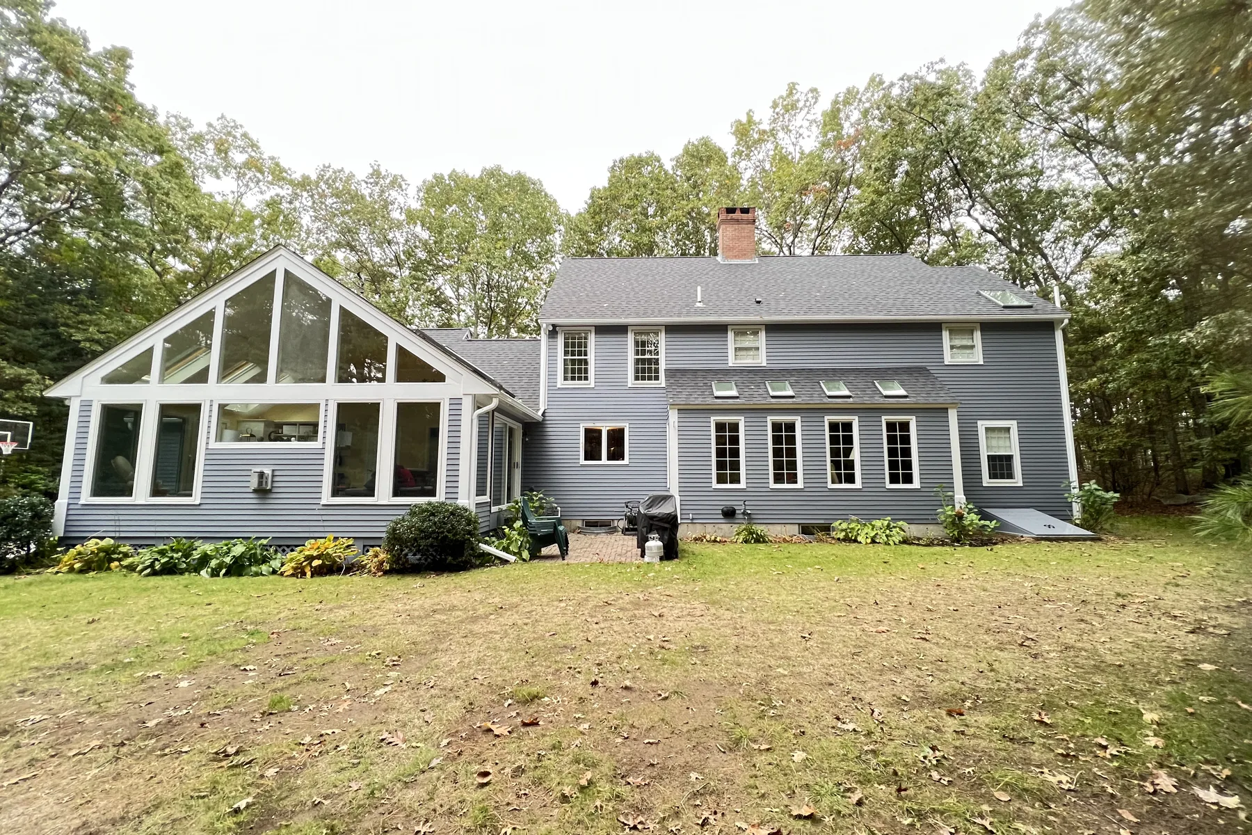 Blue colonial home with white trim and a sunroom on a DeFaria Construction project, exterior painting in Massachusetts