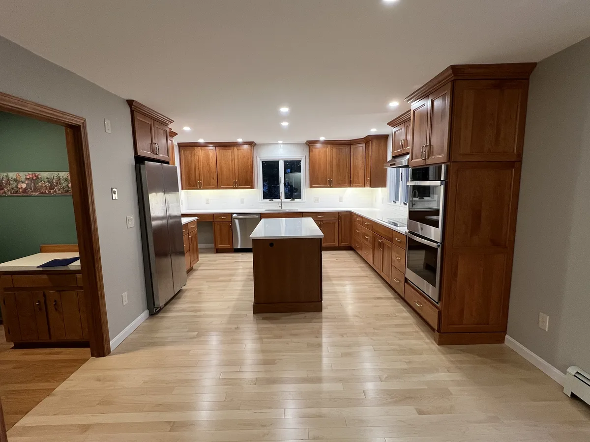 Remodeled kitchen with wood cabinets, island and light wood floors by DeFaria Construction