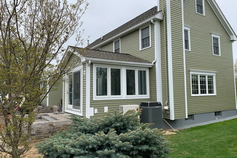 Sunroom addition with a wall of windows matching the existing siding in Westford, MA, built by DeFaria Construction, home addition contractors in Massachusetts