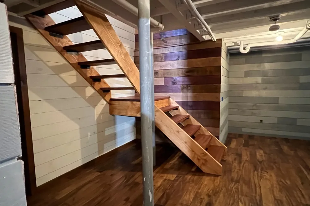 Finished basement with open stairs and shiplap accent wall by DeFaria Construction