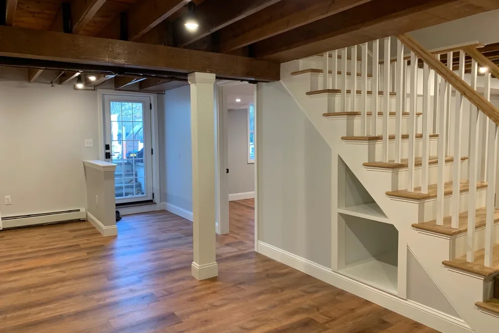 Dry finished basement with painted beams and wood-look floor by DeFaria Construction