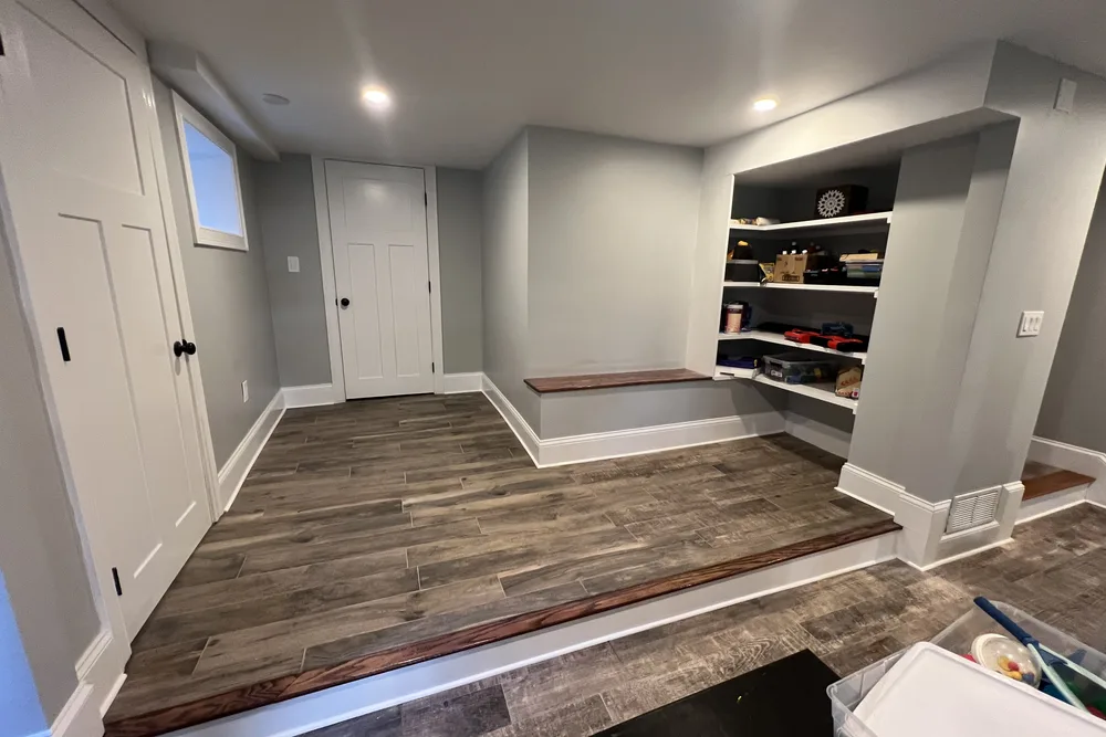Finished basement with built-in shelving and wood-look floor by DeFaria Construction