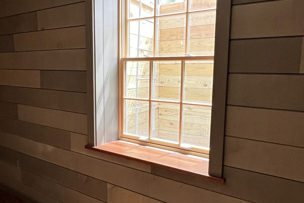 Insulated basement wall finished with shiplap and a trimmed window by DeFaria Construction
