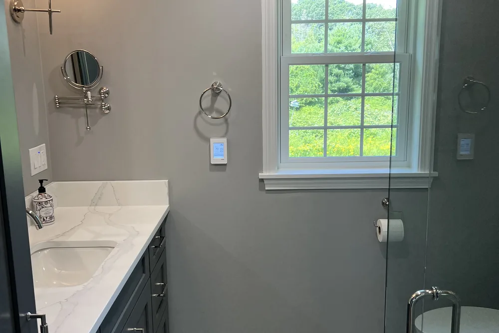 Remodeled gray bathroom with white quartz vanity top and window by DeFaria Construction