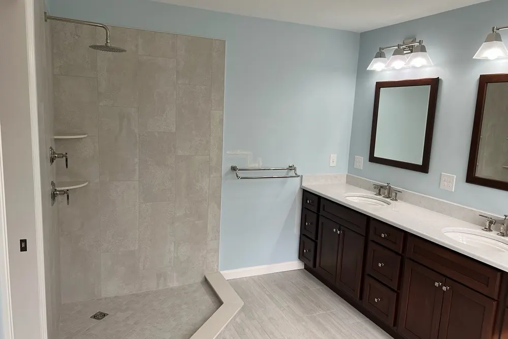 Bathroom remodel with curbless tile shower and dark double vanity in Westford, MA, by DeFaria Construction