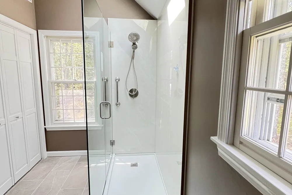 Glass shower with white wall tile and window in a remodeled bathroom by DeFaria Construction