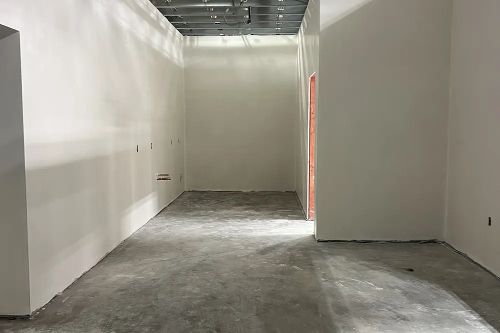 Commercial corridor with finished drywall walls and exposed steel ceiling