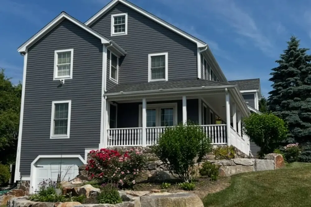 Colonial home with new siding, white window trim and a wraparound porch by DeFaria