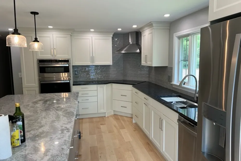 White shaker kitchen with granite island and double wall ovens in Pepperell, MA, by DeFaria Construction